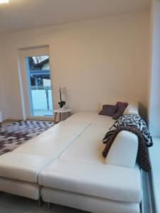 a large white bed in a room with a couch at Gemütliches 3 Zimmer Apartment nahe Graz in Gratkorn