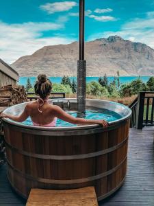 a woman in a hot tub with a view of the mountains at Hidden Lodge Queenstown in Queenstown