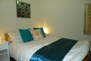 Bett mit blauer und weißer Bettwäsche und Kissen in der Unterkunft Courtyard Cottage in Knaresborough