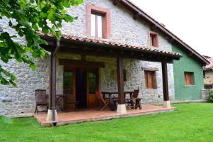 une maison en pierre avec une terrasse en bois devant elle dans l'établissement La Corte del Rondiellu 1, à Bobia de Abajo