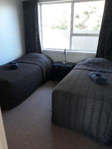 1 dormitorio con 2 camas junto a una ventana en Aalton Motel Temuka en Temuka