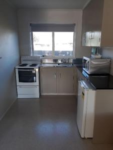 una pequeña cocina con electrodomésticos blancos y una ventana en Aalton Motel Temuka en Temuka
