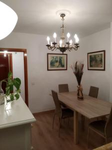a dining room with a wooden table and a chandelier at NUEVA VIVIENDA/APARTAMENTO COMPLETO EN SEVILLA in Seville