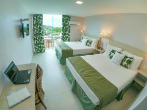 a hotel room with two beds and a laptop on a table at Hotel Experience João Fernandes in Búzios