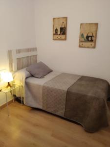 a bedroom with two beds and a lamp on the wall at NUEVA VIVIENDA/APARTAMENTO COMPLETO EN SEVILLA in Seville