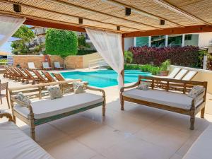 a patio with two beds and chairs next to a pool at Hotel Experience João Fernandes in Búzios