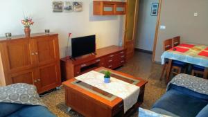 a living room with a tv and a table at Bonito apartamento para vacaciones en Puerto de Sagunto in Puerto de Sagunto