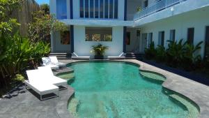 a swimming pool with two white chairs and a house at The Bali Bubble in Sanur