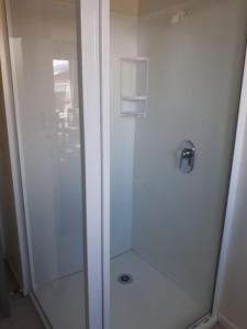 La salle de bains est pourvue d'une douche blanche avec une porte en verre. dans l'établissement Aalton Motel Temuka, à Temuka