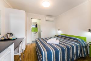 a bedroom with a white bed and white walls at Jolly Swagman Acccommodation Park in Toowoomba