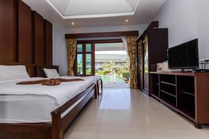 a bedroom with two beds and a television and a pool at Oscar Villa Aonang Krabi - Free Shuttle Bus to The Beach in Ao Nang Beach