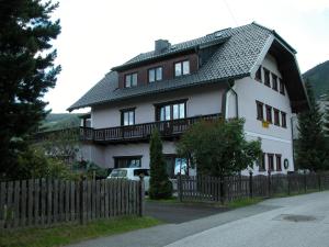 a large white house with a wooden fence at Frühstückspension Laßhofer in Mauterndorf