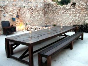 a wooden picnic table with three wine glasses on it at Homer's View in Stavros