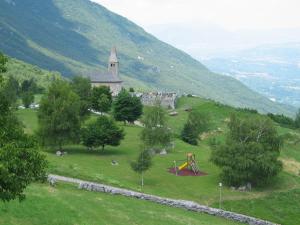 a building on a hill with a playground and a church at Albergo Bellavista in Cavedago