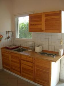 een keuken met houten kasten, een wastafel en een raam bij NIKOS in Kakóvatos