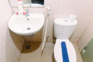 a bathroom with a white toilet and a sink at Compact Studio Room at Tamansari Papilio Apartment By Travelio in Surabaya