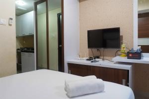 a hotel room with a bed and a television at Compact Studio Room at Tamansari Papilio Apartment By Travelio in Surabaya