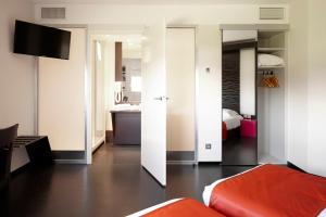 ein Wohnzimmer mit Sofa und ein Schlafzimmer in der Unterkunft Hôtel Gardenia Bordeaux Est in Yvrac