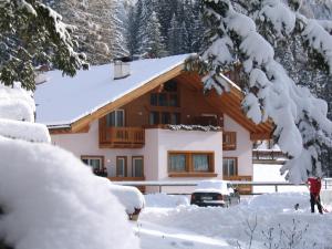a house covered in snow in front of it at Hotel Garni Civetta in Selva di Cadore