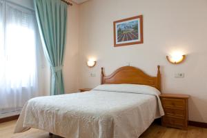a bedroom with a bed with a wooden headboard and a window at Hostal Zamora in Madrid