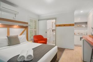 a bedroom with a bed and a red chair at Pleasant Way River Lodge in Nowra