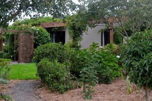 un jardín con arbustos y una casa con un edificio en Highlands on Homestead, en Oamaru