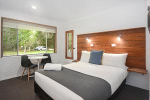a bedroom with a bed and a desk and a window at Pleasant Way River Lodge in Nowra