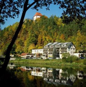 un edificio sentado en la cima de una colina junto a un lago en Hotel Am Schlossberg en Ziegenrück