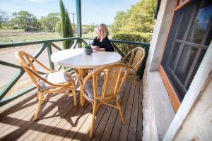 eine Frau, die an einem Tisch auf einem Balkon sitzt in der Unterkunft Old Swanport General Store, Swanport-Murray River in Swanport