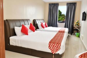 Hotel Raub Agro في راوب: غرفة نوم بسريرين ومخدات حمراء