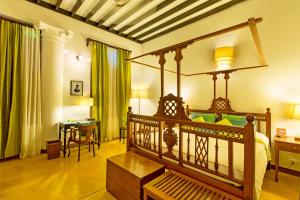 a bedroom with a canopy bed with a desk and a table at Maison Perumal Pondicherry - A CGH Earth Experience in Pondicherry