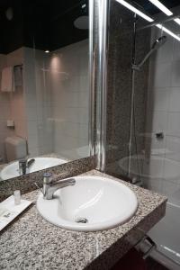 ein Bad mit einem Waschbecken und einer Dusche in der Unterkunft Hotel Gratte-Ciel Ariana in Villeurbanne