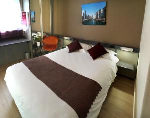 a bedroom with a bed with white sheets and brown pillows at Hotel Gratte-Ciel Ariana in Villeurbanne