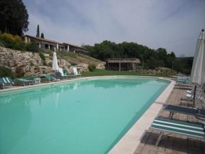 une grande piscine bleue avec des chaises et des parasols dans l'établissement Tenuta Pizzogallo, à Amelia