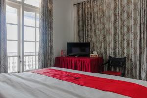 a bedroom with a bed and a television and a chair at RedDoorz Syariah near Universitas Negeri Padang in Padang