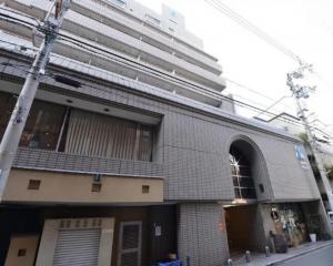 a brick building with a tall building in the background at Alphabed TakamatsuFurujinmachi 902 / Vacation STAY 21916 in Takamatsu