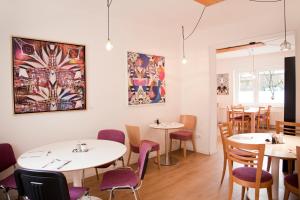 a restaurant with white tables and purple chairs at Les Nations in Berlin