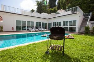 a barbecue chair sitting in the grass next to a swimming pool at Lux Pool Villas Krabi Ao Nang in Ao Nang Beach