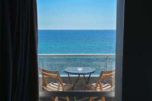 balcón con mesa y sillas y vistas al océano en Scorpios Sea Side Hotel, en Pireo