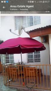ein lila Schirm auf einem Tisch mit Stühlen in der Unterkunft Mansholl Luxurious Apartment in Freetown