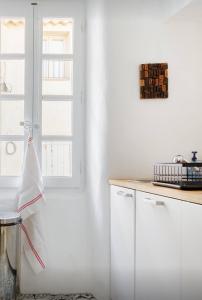 a kitchen with white cabinets and a window at Nuits étoilées Lourmarin in Lourmarin