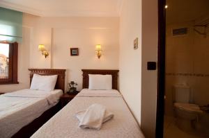 two beds in a room with a bathroom with a toilet at Emine Sultan Hotel in Istanbul