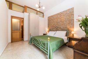 ヴィエトリにあるThe sud est houseのレンガの壁、緑のベッドが備わるベッドルーム1室が備わります。