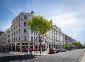 a large white building on a city street with a tree at Riu Plaza The Gresham Dublin in Dublin