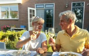 Ein Mann und eine Frau sitzen an einem Tisch mit Weingläsern in der Unterkunft Nabij de Molen in Wijdenes