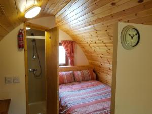 - une chambre dans une petite maison avec une horloge sur le mur dans l'établissement Colemans Cottage Fishery, à Wickham Bishops