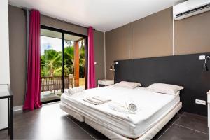 a bedroom with a large white bed with pink curtains at Le Village de la Pointe in Le Vauclin +45 photos