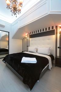 een slaapkamer met een groot zwart bed en een kroonluchter bij Partner Guest House Velyka Vasylkivska in Kiev