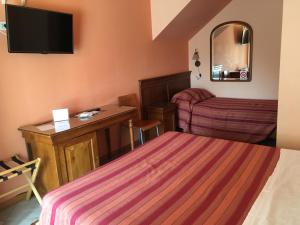 Habitación de hotel con cama, escritorio y TV. en Hotel Il Pino, en Garlasco