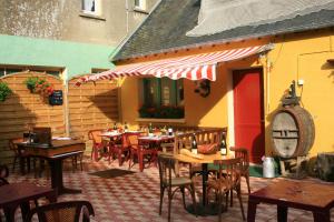 un patio extérieur avec des tables et des chaises et un bâtiment dans l'établissement Le Commerce, à La Haye-du-Puits